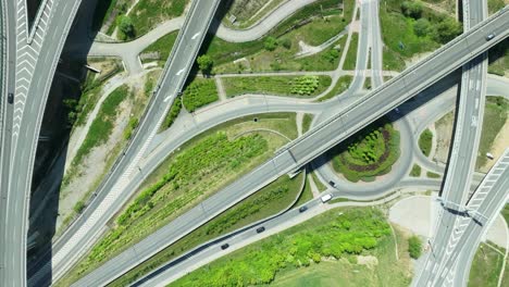 Aerial-drone-zoom-out-footage-capturing-intricate-highway-junction-with-cars-navigating-complex-roundabouts-and-intersecting-roads