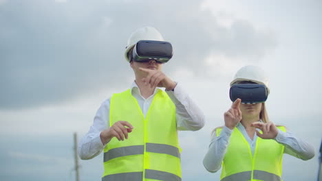 Ein-Mann-Und-Eine-Ingenieurin-Mit-VR-Brille-Steuern-Die-Stromverteilung-Von-Stromnetzen-Und-Die-Stromlieferung-Vor-Dem-Hintergrund-Von-Strommasten-Mit-Hochspannungskabeln