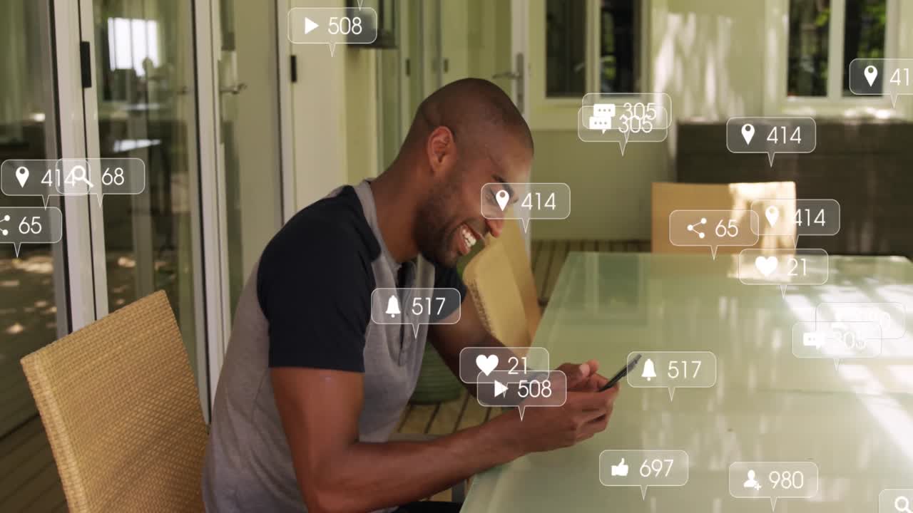 Animation of social media icons floating against african american man using smartphone at home