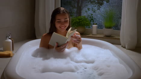 woman enjoying a relaxing bubble bath while reading a book