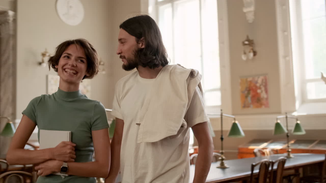 즐겁게 젊은 학생들이 도서관을 걸어다니고 있습니다.