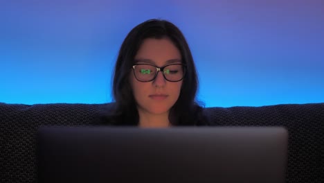 cámara lenta de una estudiante universitaria haciendo deberes en una computadora portátil por la noche cerca