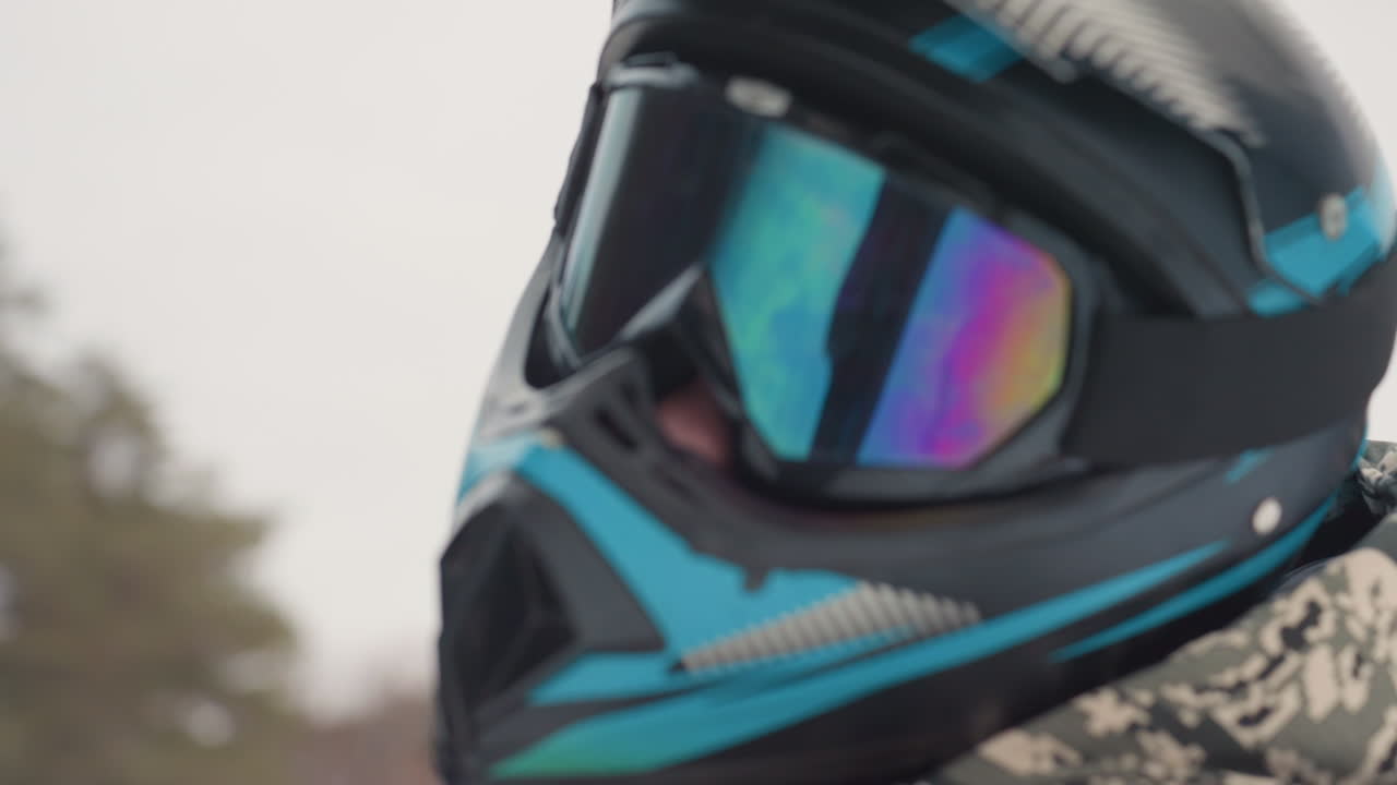 Atv helmet closeup gear inspection, mirrored goggles and textured visor, camo jacket edge, vent and strap details, close lens reflection, maintenance vibe, precise technical focus on materials