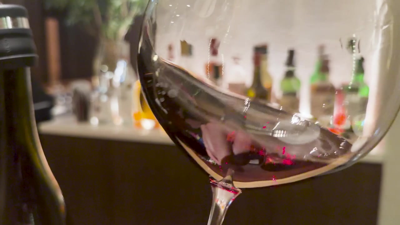 Primo piano di vino rosso che volteggia in un bicchiere in un bar ristorante in penombra.