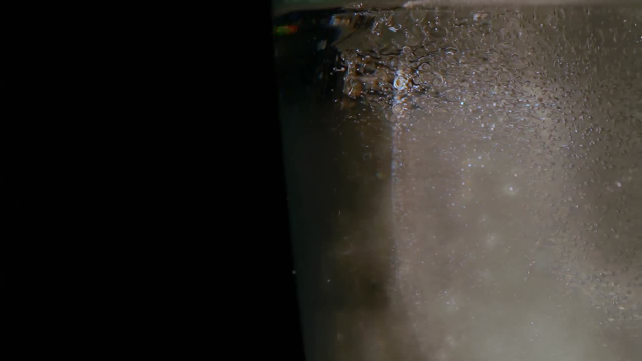 vidrio con hielo y agua contra un fondo negro 4k