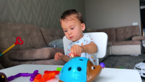 beautiful calm child playing peacefully at home. baby boy sits at desk busy with his toys.