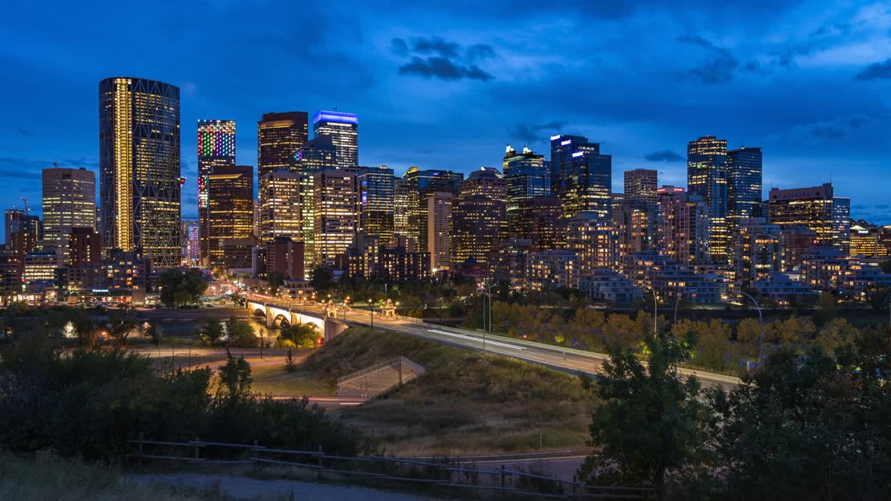 calgary, alberta, canadá, vista en lapso del horizonte de calgary que muestra edificios modernos en el distrito financiero al anochecer