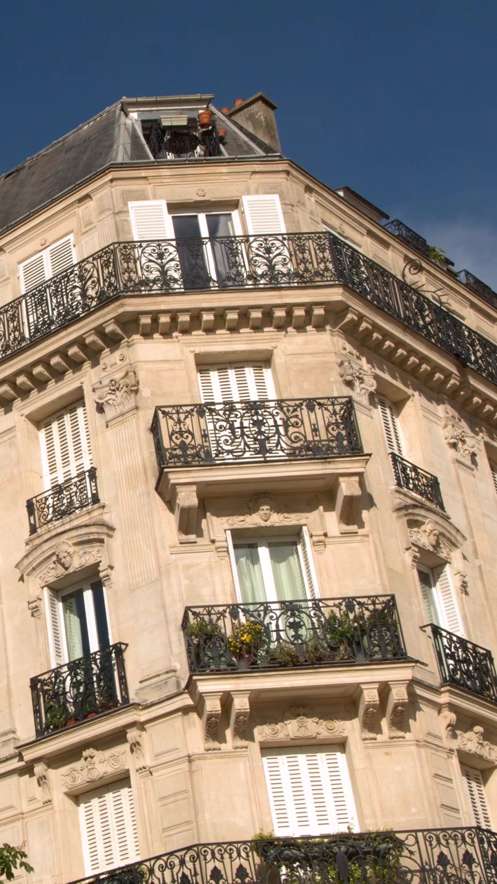 Vista dal basso di architettura francese storica con balconi ornati sotto un cielo azzurro limpido
