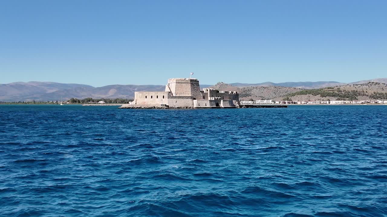 Peloponeso, Nauplia. Vista aérea frontal hacia el castillo de Bourtzi desde el mar azul intenso durante el día. Detrás se encuentra la ciudad de Nauplia al fondo. Sin personas