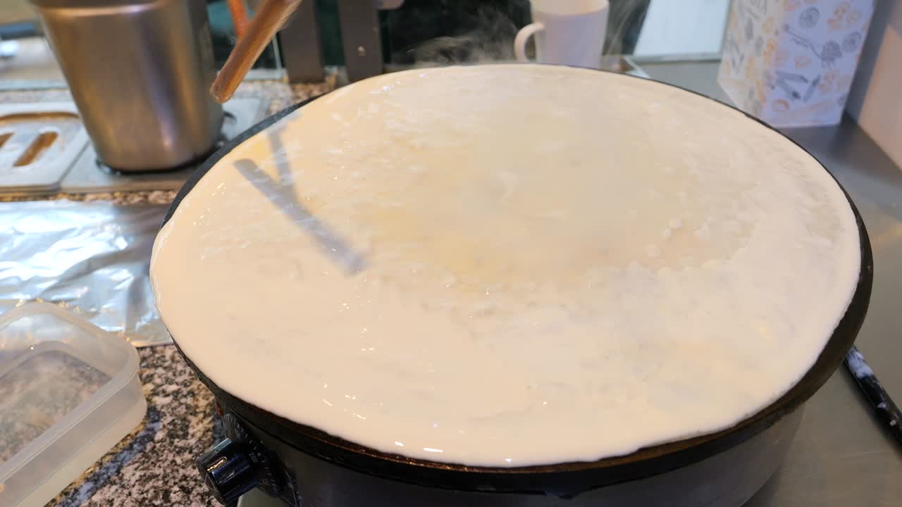 셰프는 스파로 팬케이크 반죽을 팬에 뿌립니다.