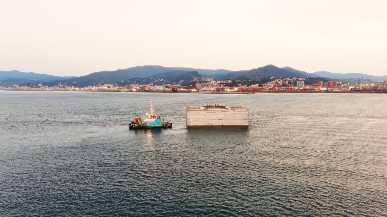 Industrial towboat operating at sunset in an Italian port. Aerial