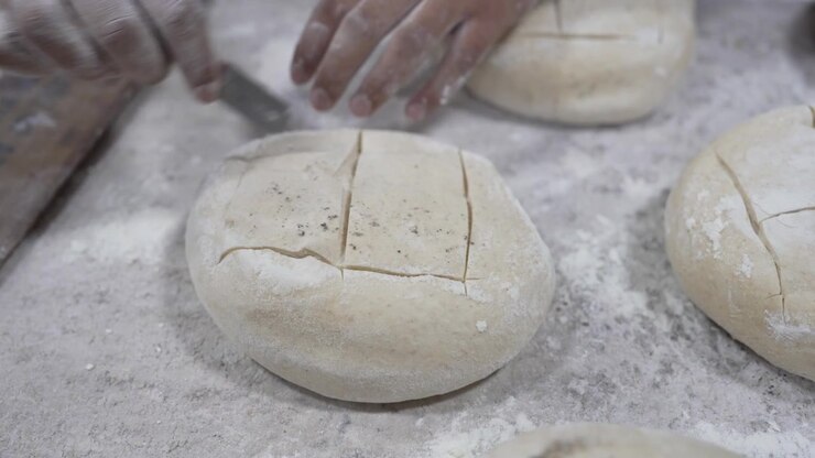 A woman rolling dough in a private bakery, captured in 4K resolution at 60fps, slow motion. The artisan process highlights traditional breadmaking as she prepares the dough in a rustic setting