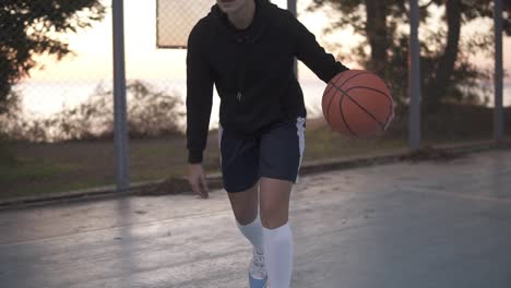 handhelded footage of a young girl basketball player training and exercising outdoors on the local court