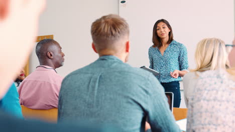 una tutora universitaria con una tableta digital enseña a estudiantes maduros