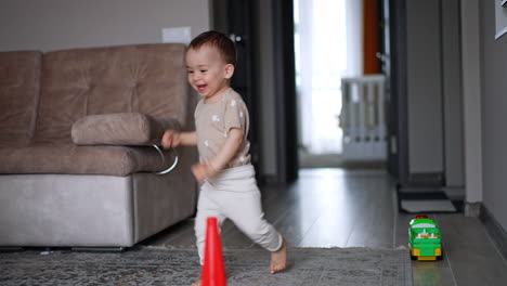 happy caucasian boy runs into the room cheerfully. little kid goes past the toys on the floor.