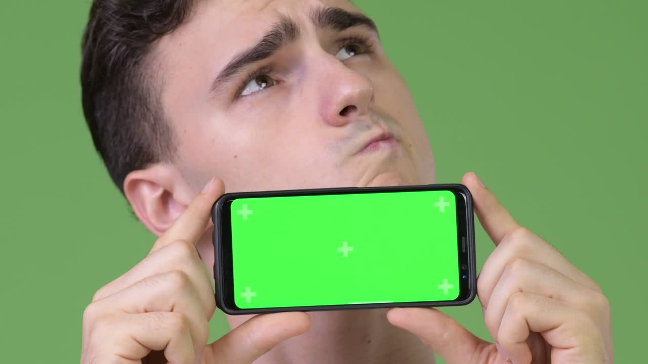 Young handsome man showing phone and thinking
