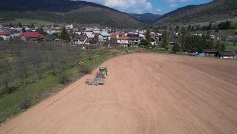 aerial view of tractor pulling heavy rollers to flatten field soil, countryside