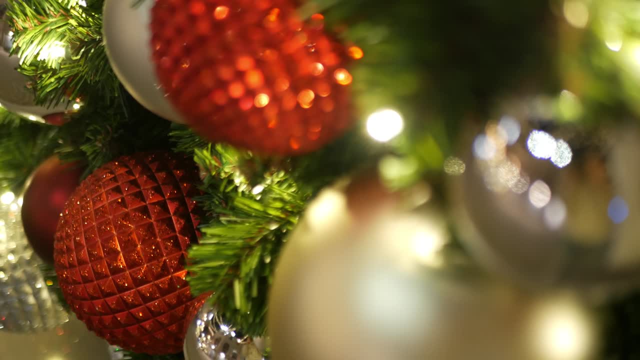 primer plano de un árbol de navidad al aire libre decorado festivamente con bolas rojas brillantes en un fondo de hadas brillantes borrosas. luces de guirnaldas desenfocadas, efecto bokeh. feliz navidad y feliz concepto de vacaciones.