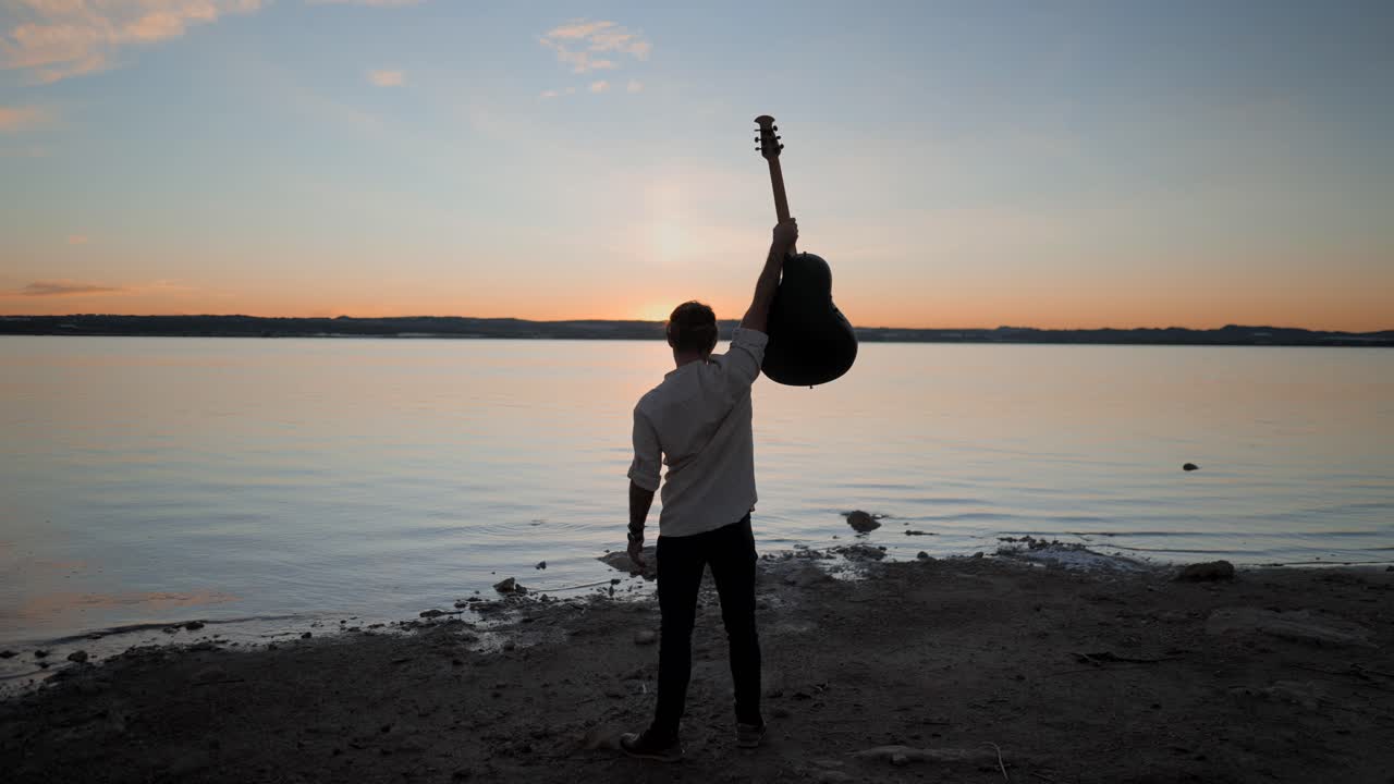 Man with Guitar at Sunset on the Lake Shore