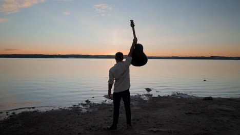 Man with Guitar at Sunset on the Lake Shore