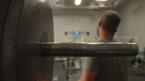 man's hands sliding 45 pound weight plate off of barbell, close up, slow motion