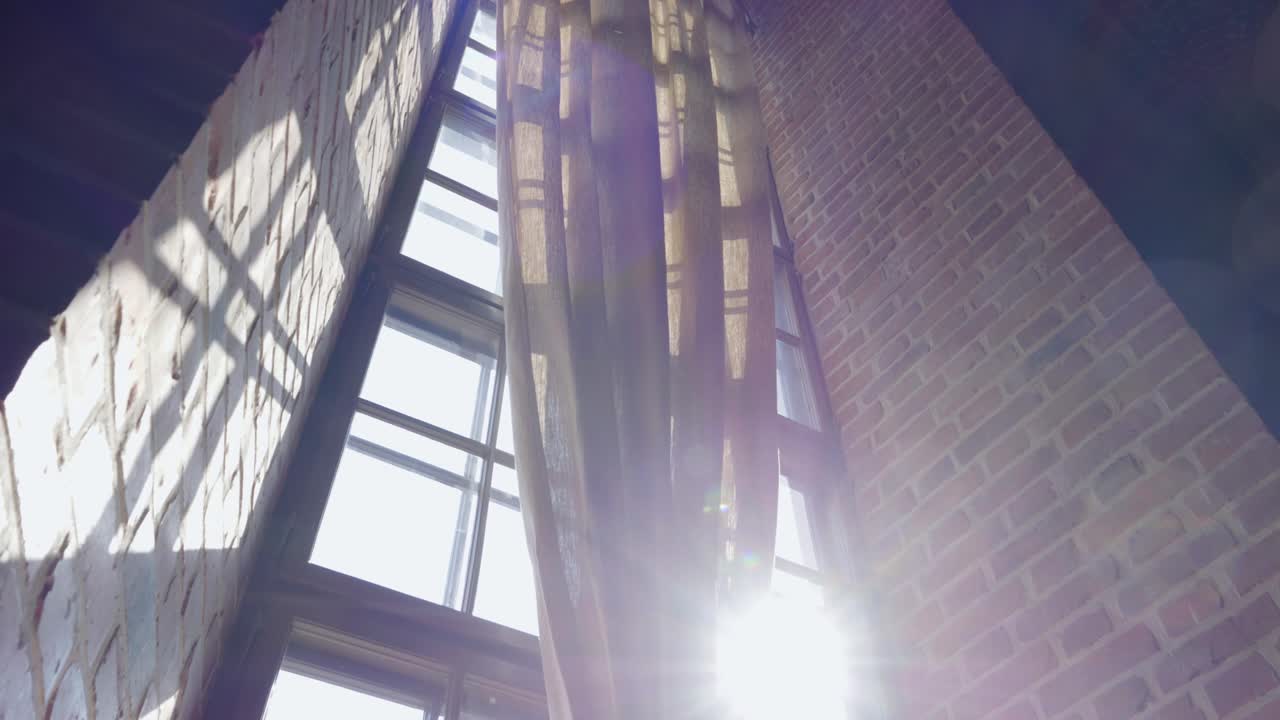 Sunlight streaming through a tall, pointed window set into a thick, massive wall of a Gothic castle