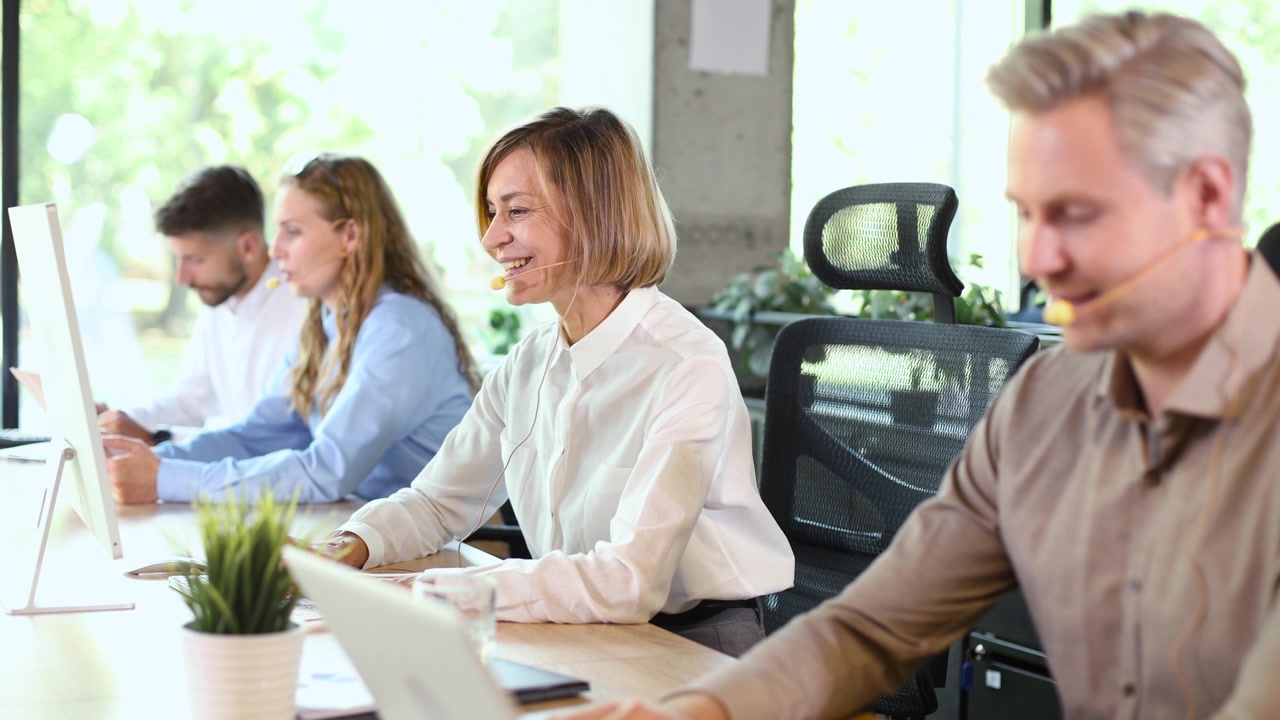Team diversificato di call center che lavora con cuffie in un ufficio moderno