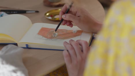 artist woman coloring book with water paint, close up