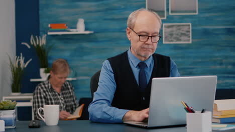 Retired-manager-sitting-at-desk-in-front-of-camera-smiling