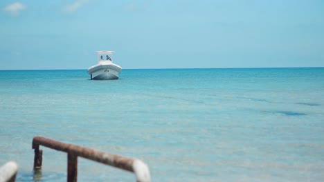 A-small-rubber-sided-boat-anchors-in-the-Mediterranean-near-the-coastline,-basking-in-the-sunny,-clear-weather-amidst-the-crystal-clear-blue-waters