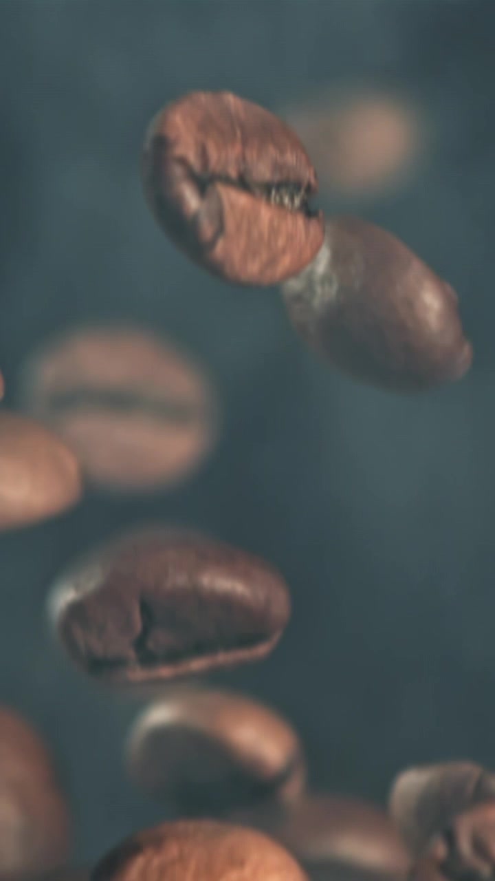 Movimento rallentato di chicchi di caffè tostati che cadono su uno sfondo fumoso