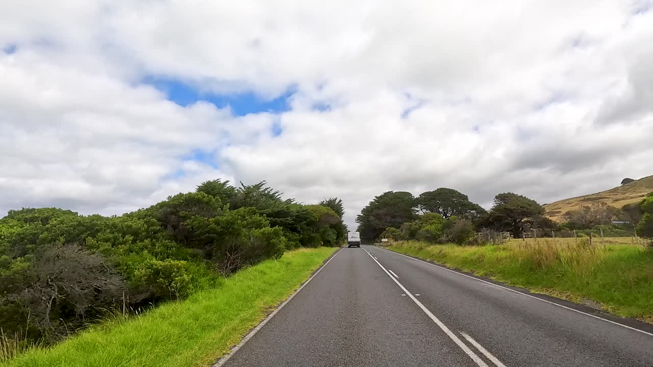 A serene drive through lush greenery and coastal views on a sunny day along the Great Ocean Road
