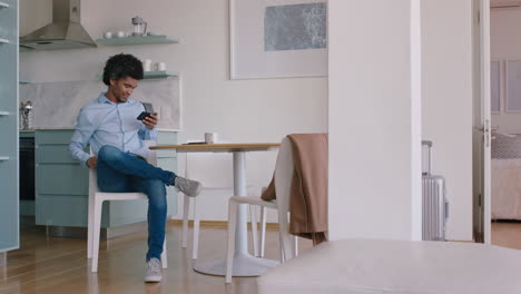 young man using smartphone texting social media messages browsing online enjoying mobile communication drinking coffee at home