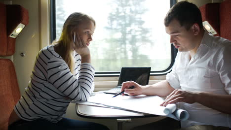 man and woman discussing drawing during business trip in the train