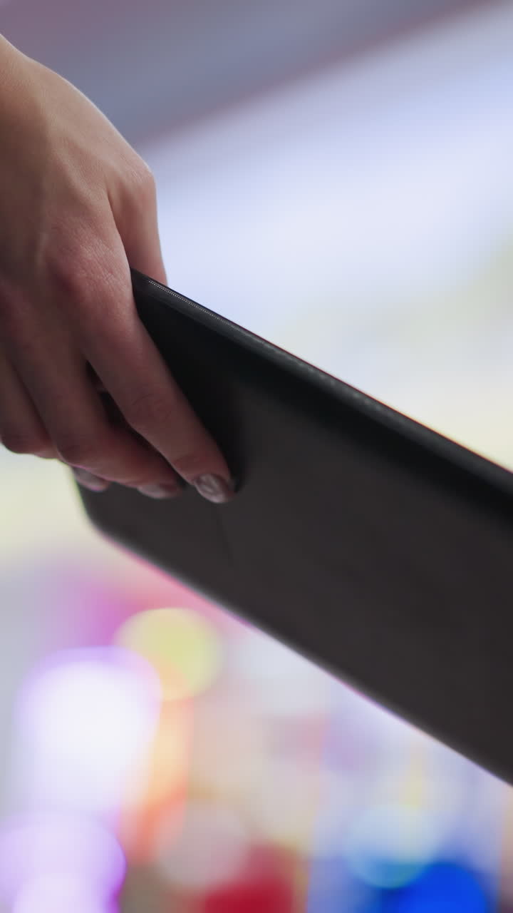 primer plano de una mujer sosteniendo una tableta en la mano con iluminación bokeh en el fondo, creando una atmósfera relajada y tecnológica en el entorno de compras