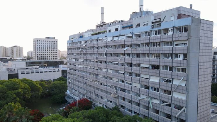 Ripresa con drone di un edificio residenziale danneggiato da missili, con finestre in frantumi e persiane rotte a Tel Aviv.