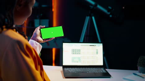 African american girl holds phone with isolated greenscreen at home,
