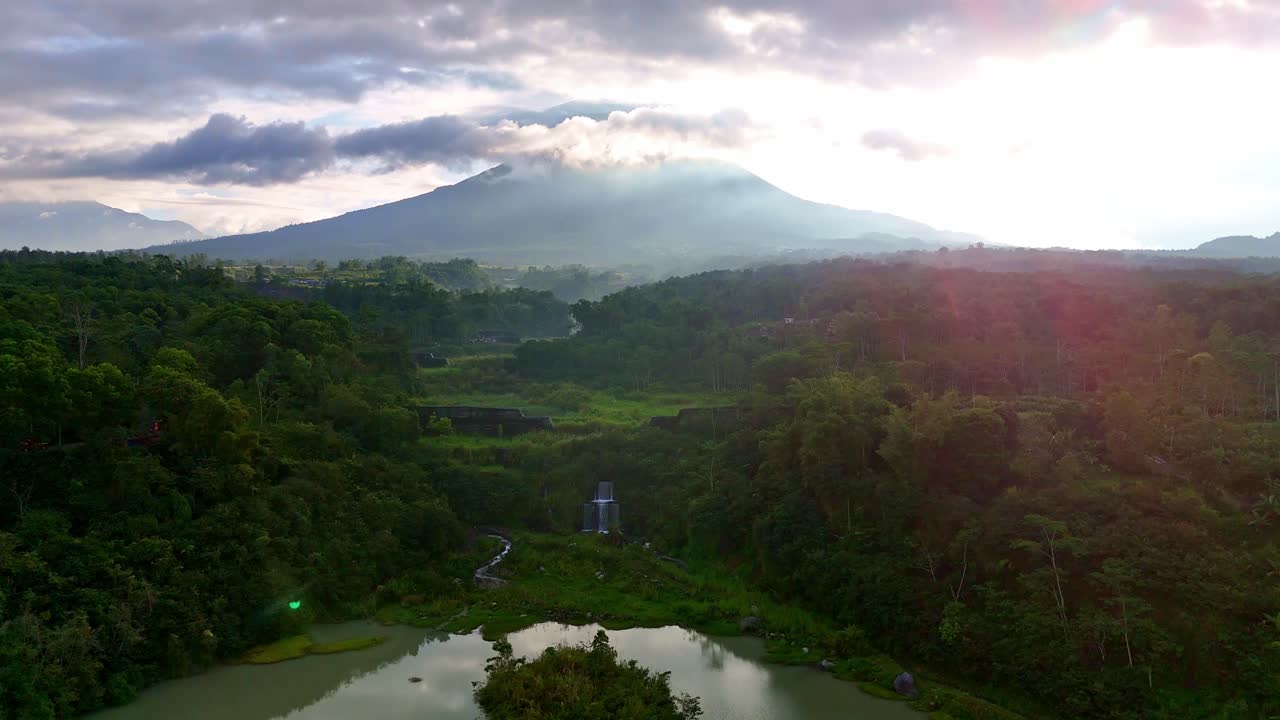 Panoramic aerial view over a lake with the Merapi volcano in the background.