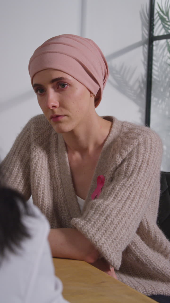 Vertical Video Of Anxious Young Woman Patient Wearing Headscarf Undergoing Chemotherapy Treatment For Breast Cancer Meeting With Oncologist Or Doctor In Hospital