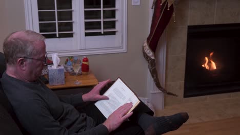 old senior man alone reading and drinking on christmas night