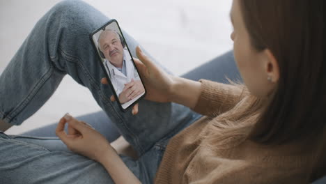 Frau-Nutzt-Medizinische-App-Auf-Smartphone-Und-Berät-Sich-Per-Videokonferenz-Mit-Dem-Arzt.-Frau-Nutzt-Online-Chat,-Um-Mit-Familientherapeuten-Zu-Sprechen-Und-Mögliche-Symptome-Während-Einer-Coronavirus-Pandemie-Zu-überprüfen.