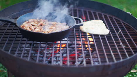 person cooking chicken and naan bread on a griddle outside while camping