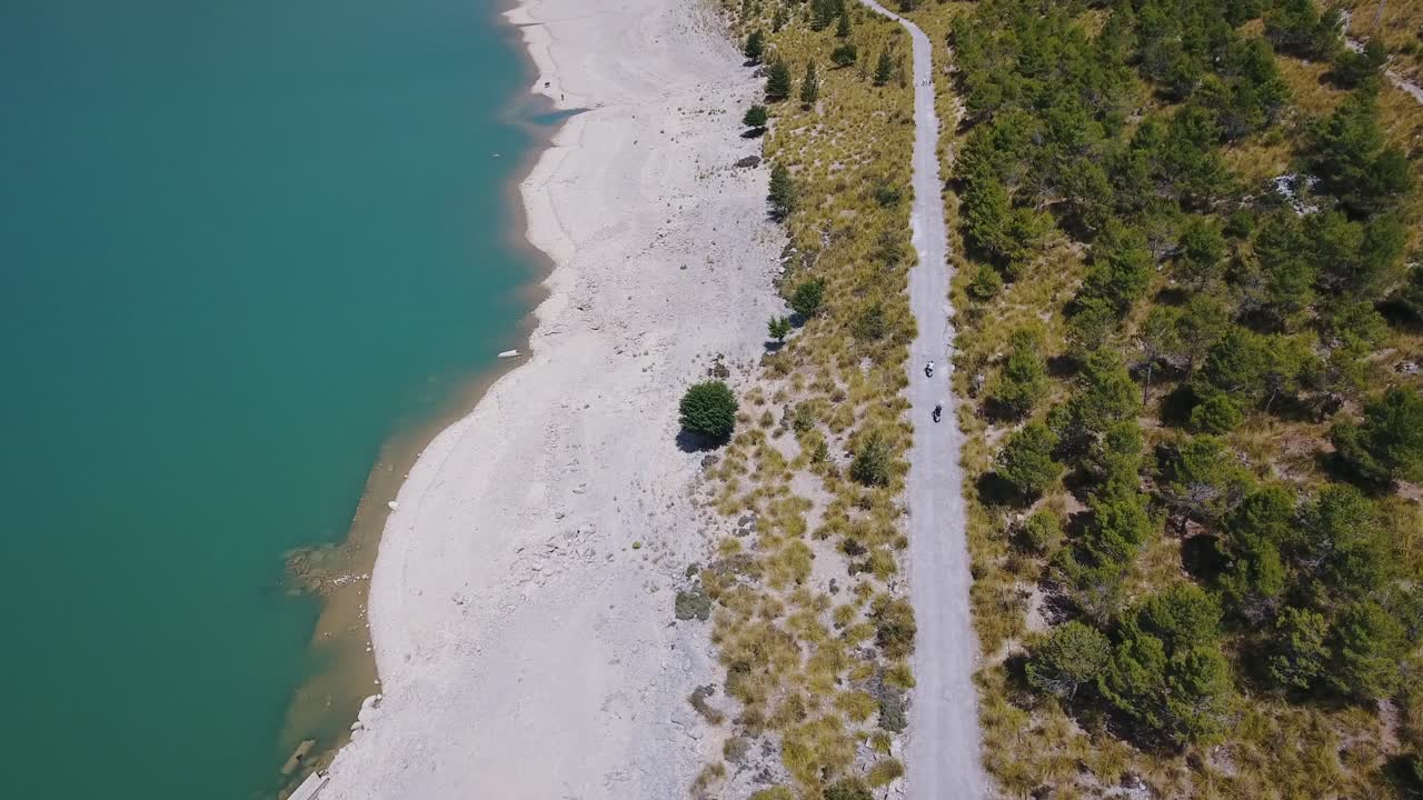 Top down shot of to scooter drivers next to a sea - water