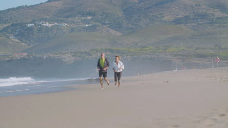 una pareja feliz y madura corriendo por la playa y divirtiéndose.