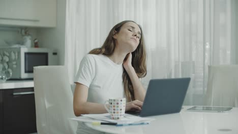 Tired-woman-working-on-laptop-computer-at-home.-Stressed-woman-touching-neck