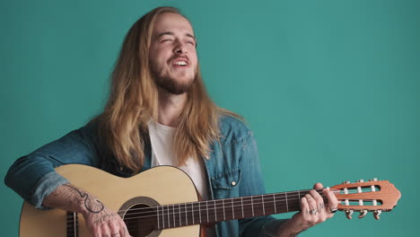 caucasian young man playing guitar and singing on camera.