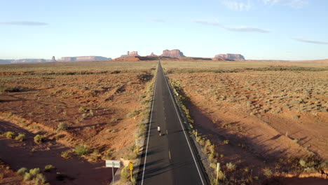 smooth drone footage of man skateboarding in monument valley along forest gump highway in utah