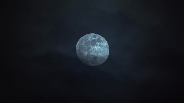 Nuvens passando em frente a uma grande lua cheia.