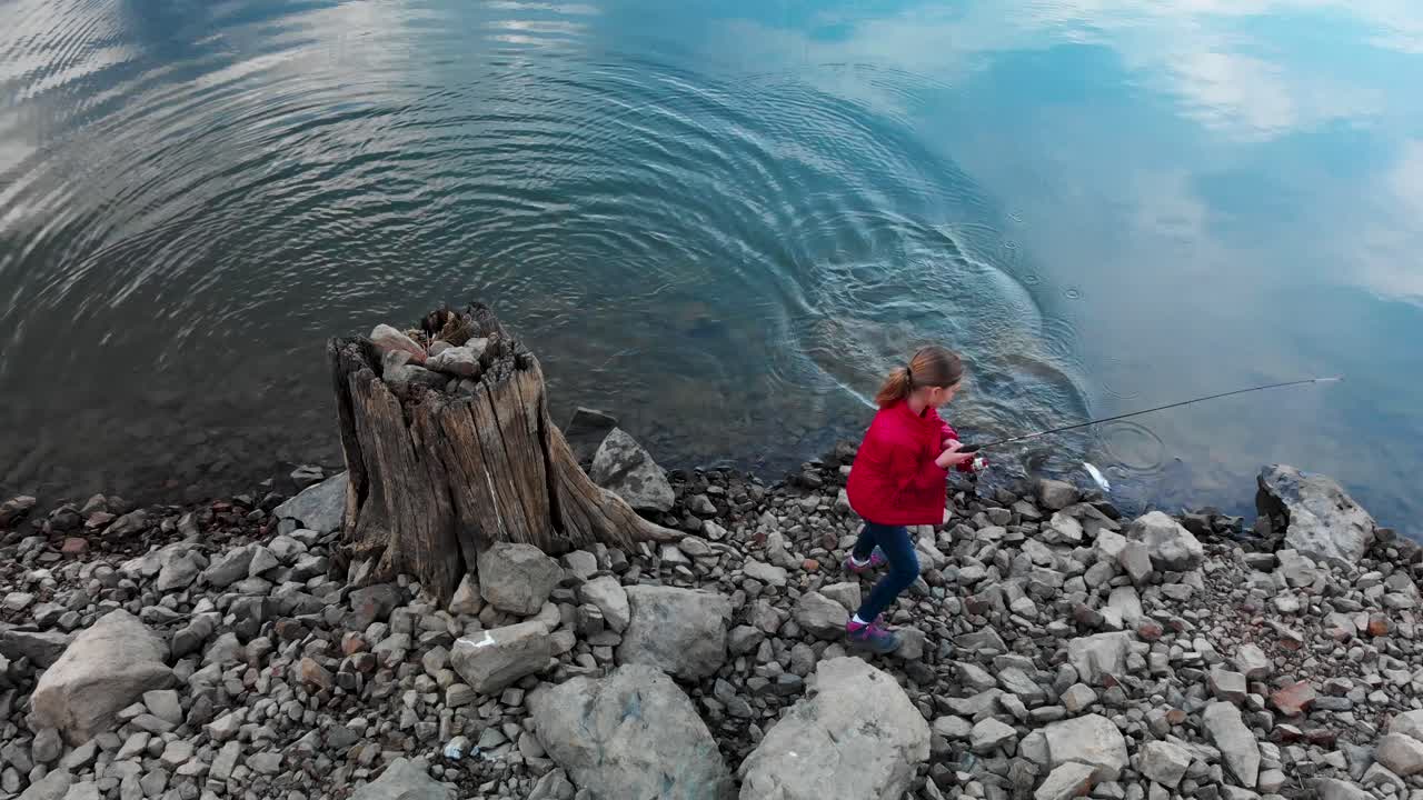 Aerial shot of young girl catching a fish on a beautiful lake