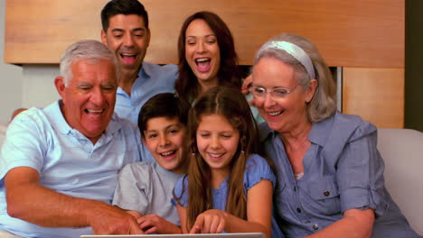 familia extendida usando computadora portátil juntos en el sofá